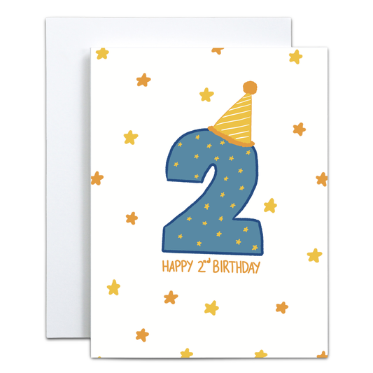 A white birthday card with a large blue number 2 decorated with small gold stars, a yellow party hat, and the words 'HAPPY 2nd BIRTHDAY' in gold. A white envelope is partially visible behind the card.