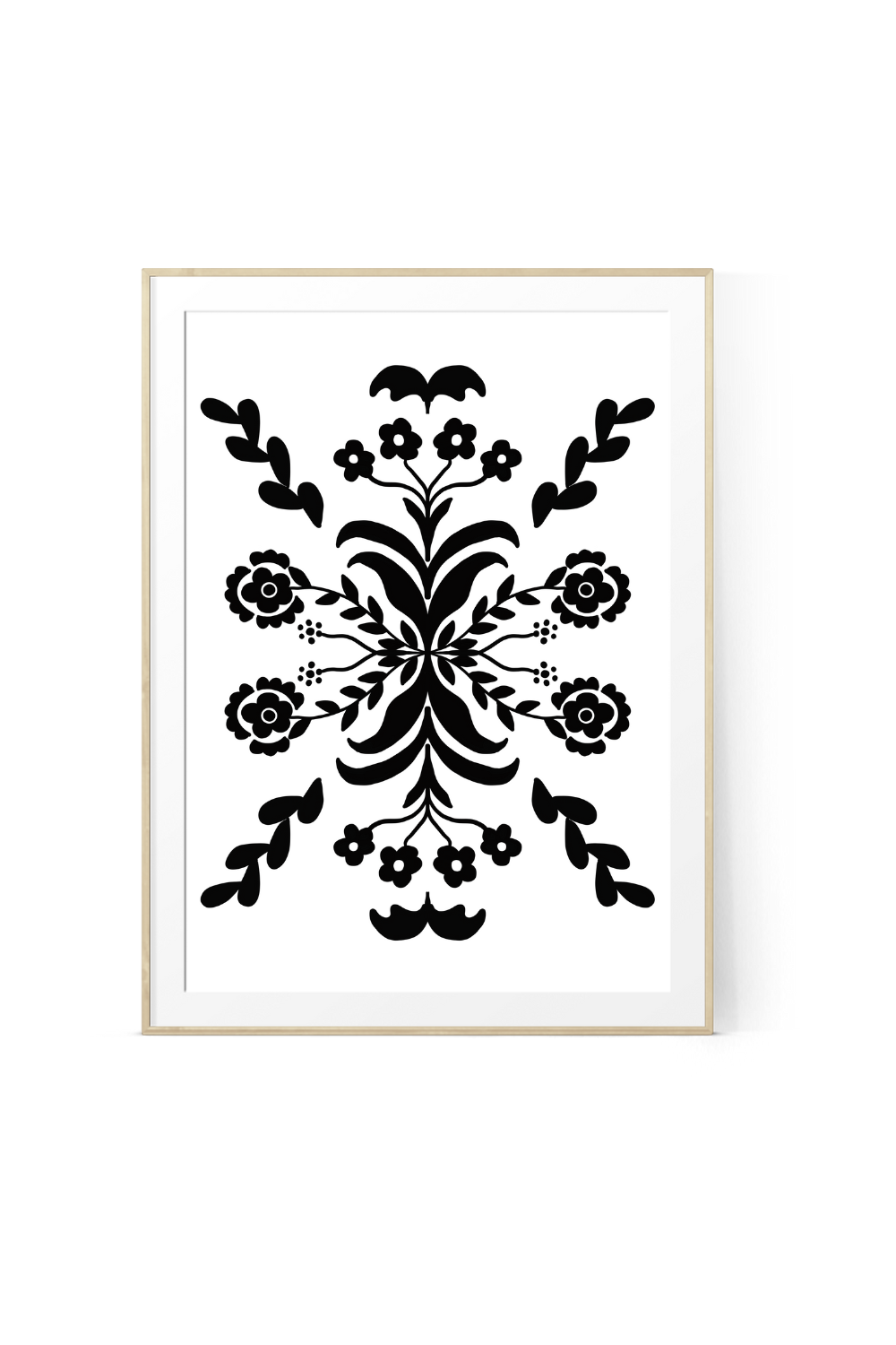 Minimalist Scandinavian folk art print featuring a bold black and white symmetrical botanical design with stylized flowers and leaves, displayed in a light wood frame against a white background.