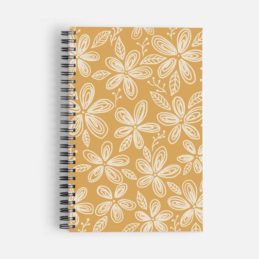 Mustard yellow spiral notebook with a white floral and botanical leaf pattern on the cover