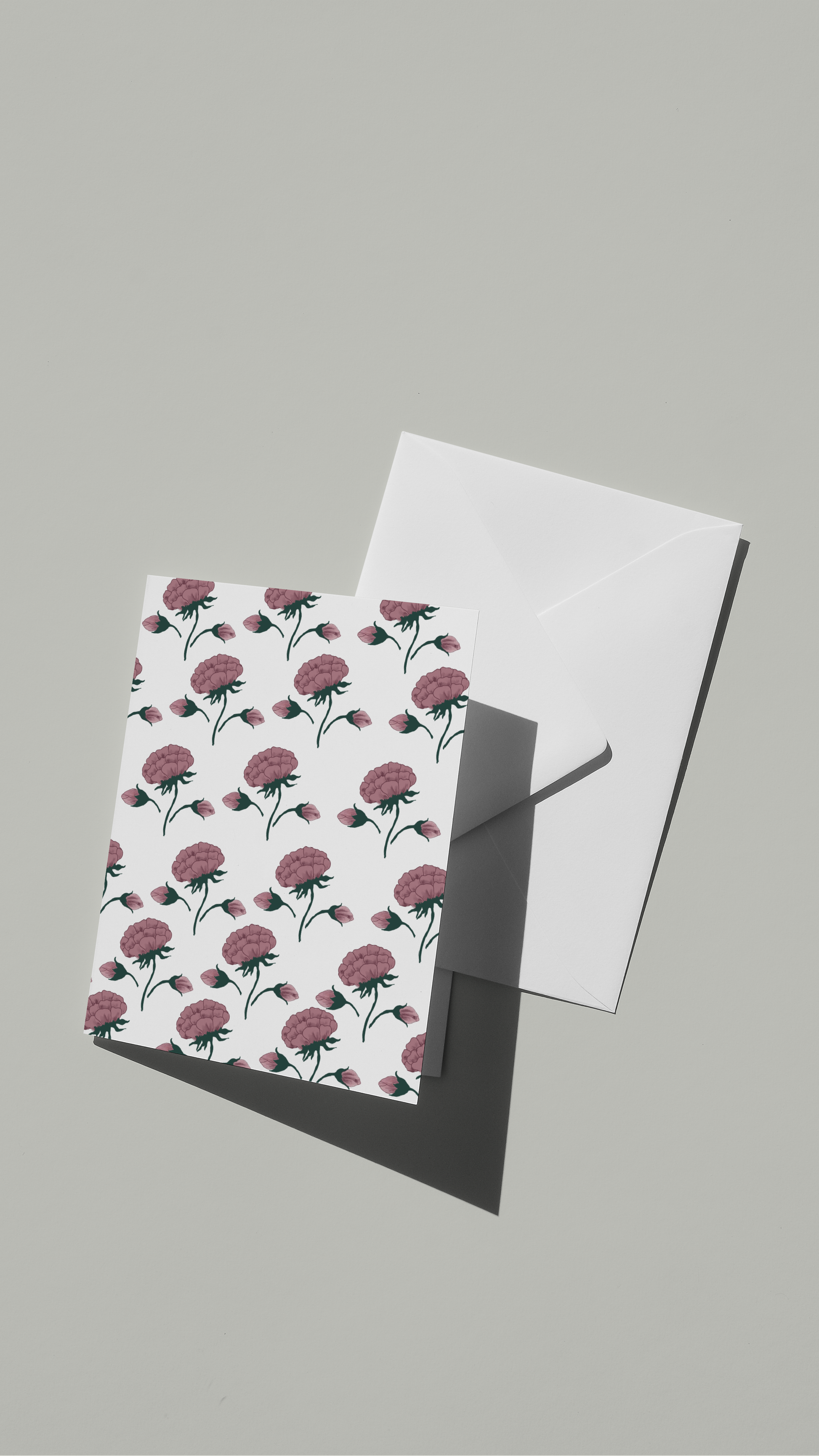 A greeting card with a floral pattern of pink mughal flowers on a white background, paired with a white envelope.